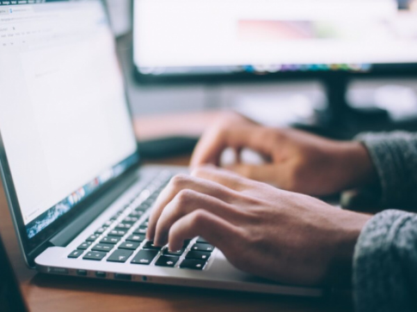 A pair of hands type on a laptop keyboard.