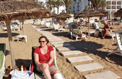 Chandra siting on a beach in Morocco with a broken leg.